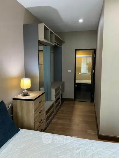 Cozy bedroom with modern furniture and soft lighting, featuring a walk-in closet.