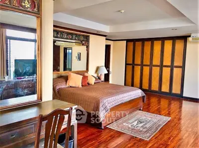 Spacious bedroom with elegant wooden flooring and stylish decor in a luxurious apartment.