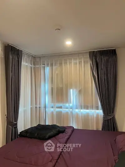 Cozy bedroom with elegant curtains and soft lighting, perfect for relaxation.