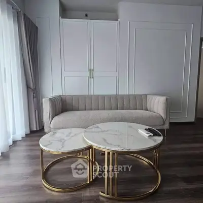 Elegant living room with modern sofa and marble coffee tables, featuring chic decor and natural light.