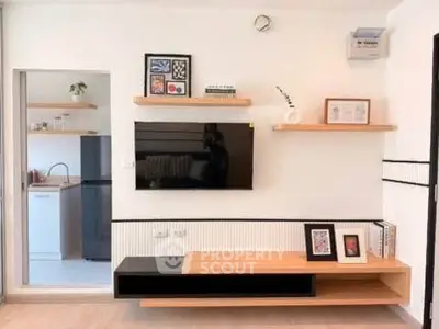 Modern living room with stylish shelves and wall-mounted TV, adjacent to a sleek kitchen area.
