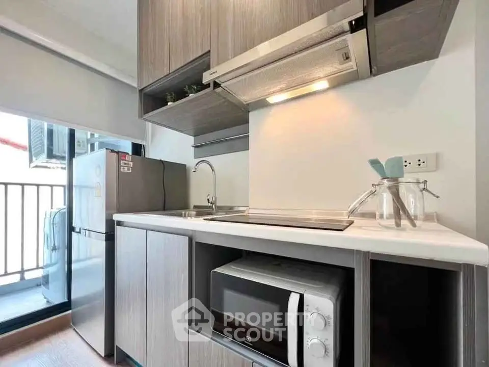 Modern kitchen with sleek cabinetry, microwave, and balcony access in a stylish apartment.
