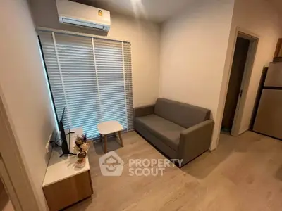 Cozy living room with modern sofa, TV, and air conditioning in a compact apartment setting.