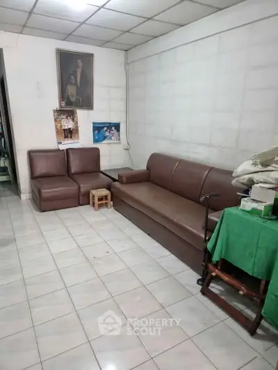 Cozy living room with brown leather sofas and tiled flooring, perfect for relaxation.
