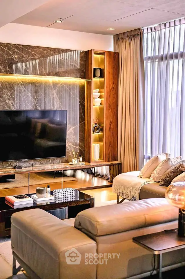 Luxurious living room with modern decor, large TV, and elegant lighting.