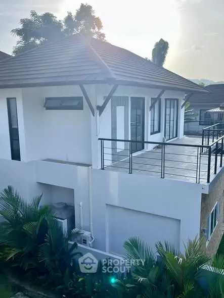 Modern two-story house with spacious balcony and lush greenery