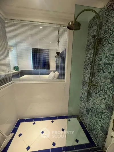 Stylish bathroom with modern shower and decorative tiles, adjacent to a cozy bedroom.
