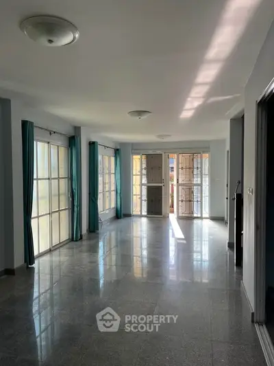 Spacious sunlit living room with large windows and elegant flooring