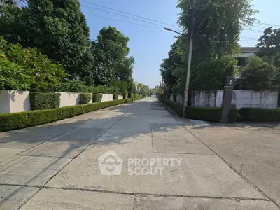 Charming residential street with lush greenery and well-maintained hedges, perfect for serene living.