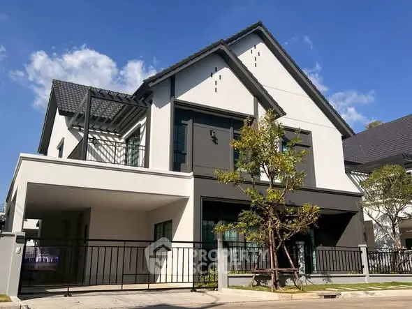 Modern two-story house with sleek design and spacious driveway under clear blue sky.