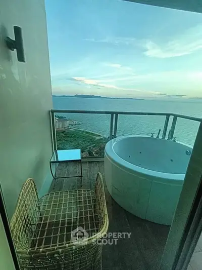 Luxurious balcony with jacuzzi offering stunning ocean views at sunset.