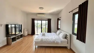 Spacious bedroom with modern decor and large windows offering natural light.