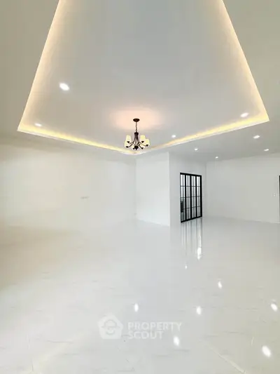 Spacious modern living room with elegant ceiling lights and glossy white flooring, perfect for luxury living.