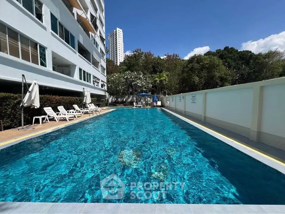 Luxurious residential pool with sun loungers and lush greenery, perfect for relaxation and leisure.