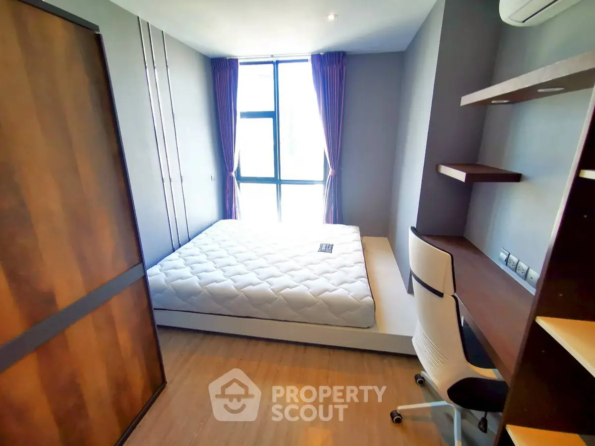 Modern bedroom with large window and stylish furniture in a cozy apartment.