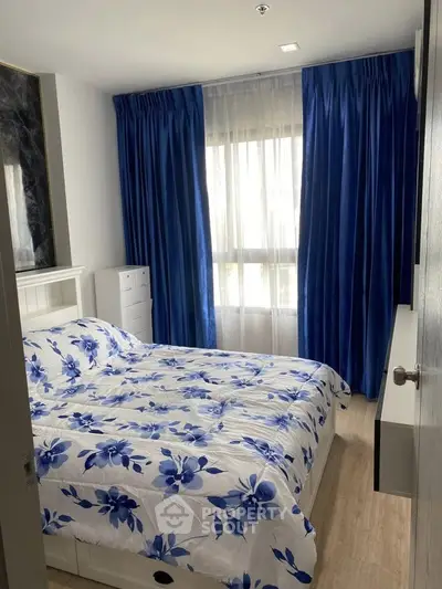 Cozy bedroom with floral bedding and elegant blue curtains, perfect for relaxation and comfort.