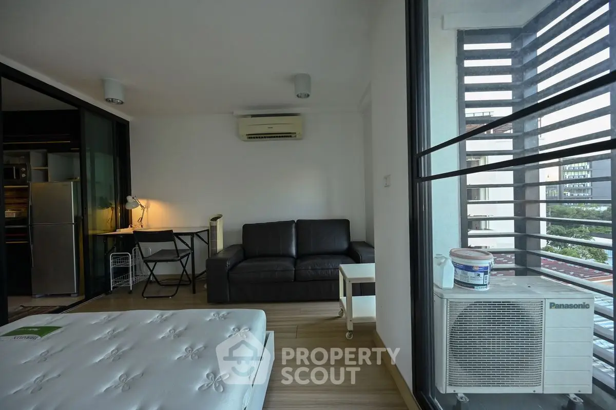 Modern studio apartment with balcony and air conditioning, featuring sleek furniture and natural light.