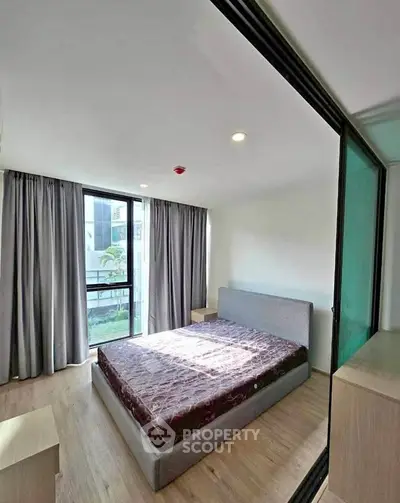 Modern bedroom with large window and stylish decor in a contemporary apartment.