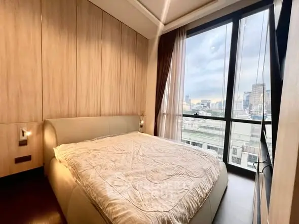 Modern bedroom with large windows offering stunning city views in a high-rise apartment.