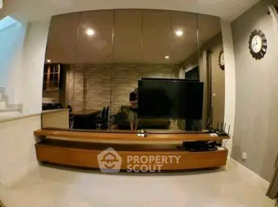 Modern living room with sleek TV unit and mirrored wall for spacious feel.