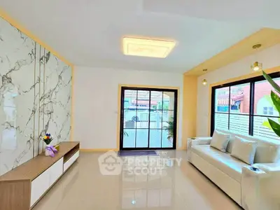 Bright modern living room with marble accent wall and large window view.