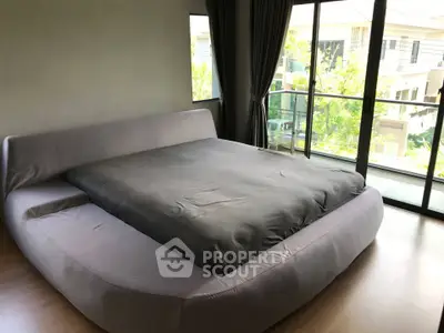 Spacious bedroom with large bed and floor-to-ceiling windows overlooking greenery.