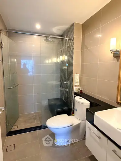Modern bathroom with glass shower, sleek fixtures, and elegant lighting.