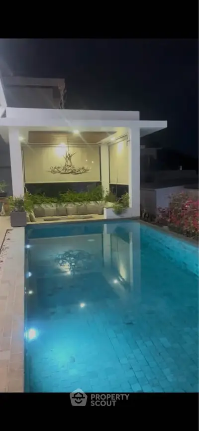 Luxurious night view of a modern poolside with elegant lighting and lush greenery.