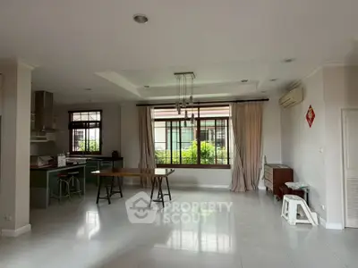Spacious open-plan living area with large windows and modern kitchen in a bright, airy home.