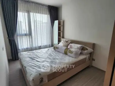 Modern bedroom with large window and stylish decor in a high-rise apartment.