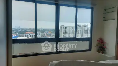 Bright bedroom with large window offering stunning city view in modern apartment.