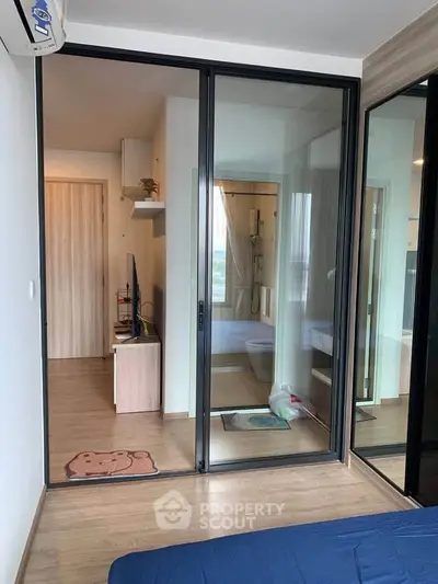 Modern apartment interior with glass partition and wooden flooring, featuring a cozy living space.