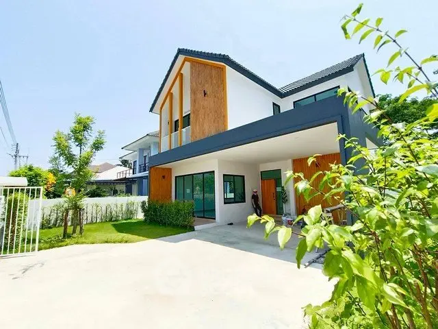 Modern two-story house with spacious driveway and lush greenery, perfect for family living.