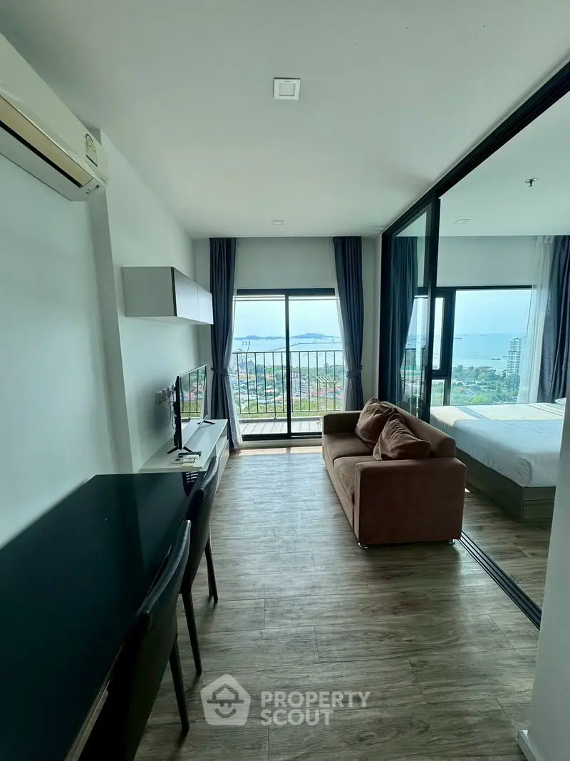 Modern living room with stunning ocean view and balcony access in a high-rise apartment.