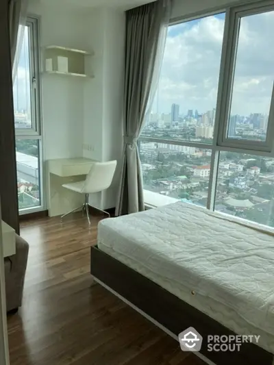 Modern bedroom with city view, featuring large windows and stylish furnishings.