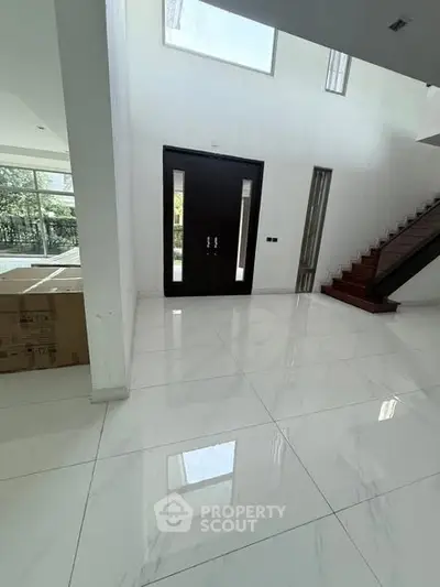Spacious modern entrance with glossy white tiles and elegant staircase