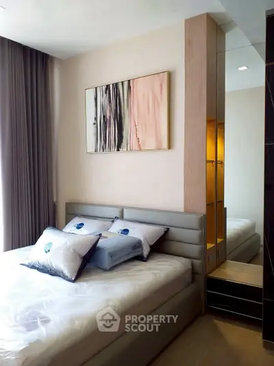 Modern bedroom with stylish decor and natural light, featuring a comfortable bed and elegant artwork.
