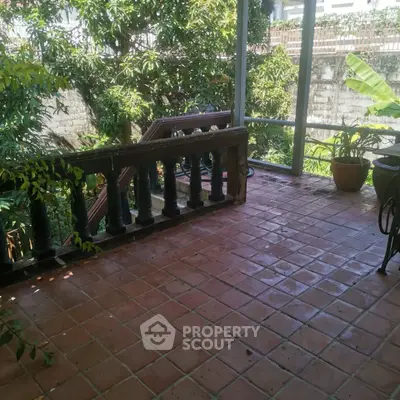 Charming outdoor balcony with terracotta tiles and lush greenery, perfect for relaxation and enjoying nature.