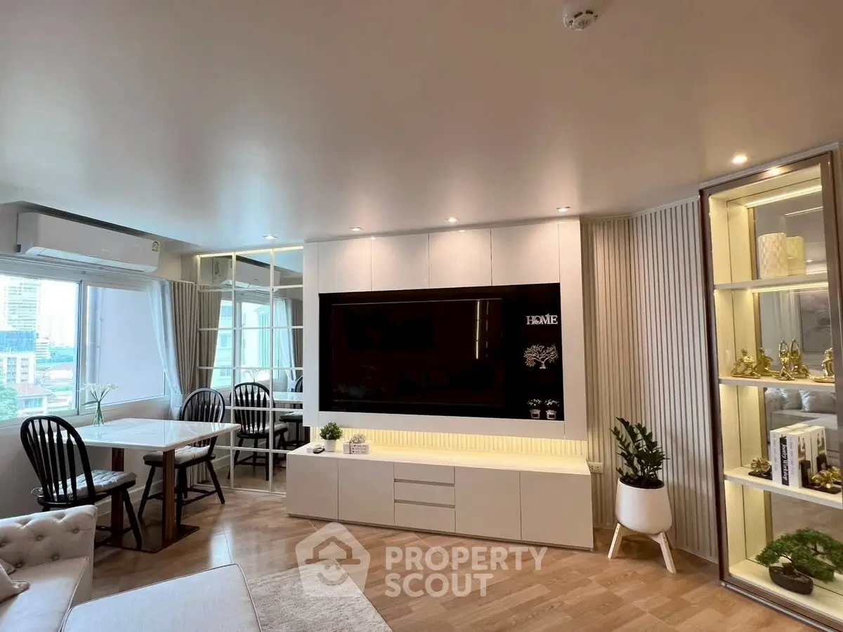 Modern living room with large TV, stylish decor, and dining area with city view.