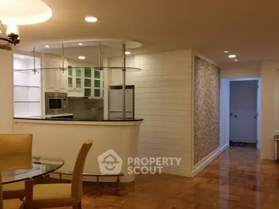 Modern open-layout kitchen with sleek design and dining area, featuring stylish lighting and parquet flooring.