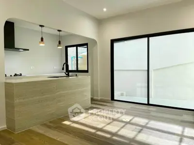 Modern kitchen with open layout and sleek design, featuring large windows and stylish lighting.
