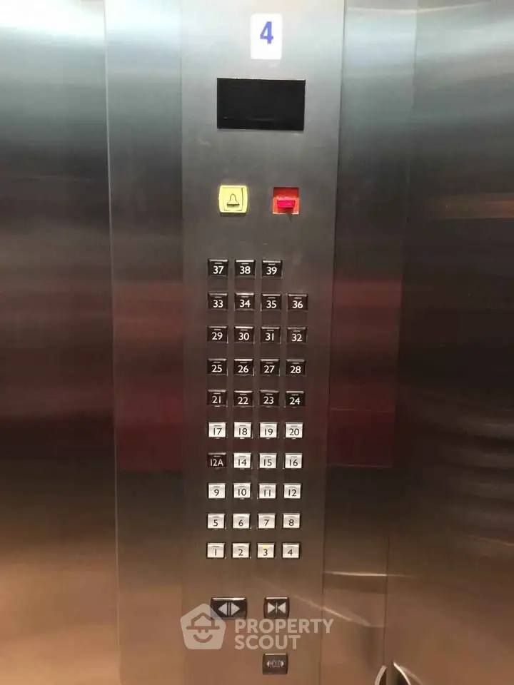 Modern elevator interior with stainless steel panel and floor buttons in a high-rise building.