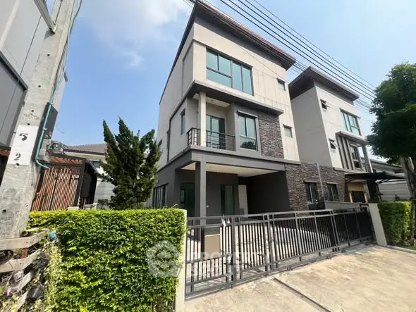 Modern three-story townhouse with sleek design and gated entrance in a suburban neighborhood.