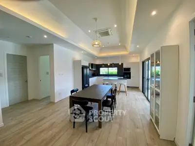 Spacious modern kitchen with open layout and dining area, featuring sleek appliances and elegant lighting.