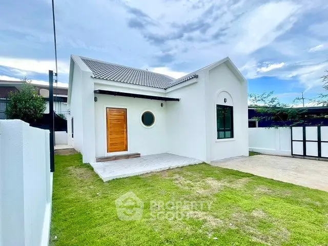 Charming white single-story house with lush green lawn and modern design.