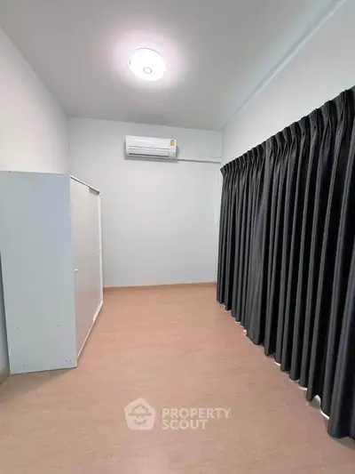 Spacious minimalist bedroom with air conditioning and large window curtains.