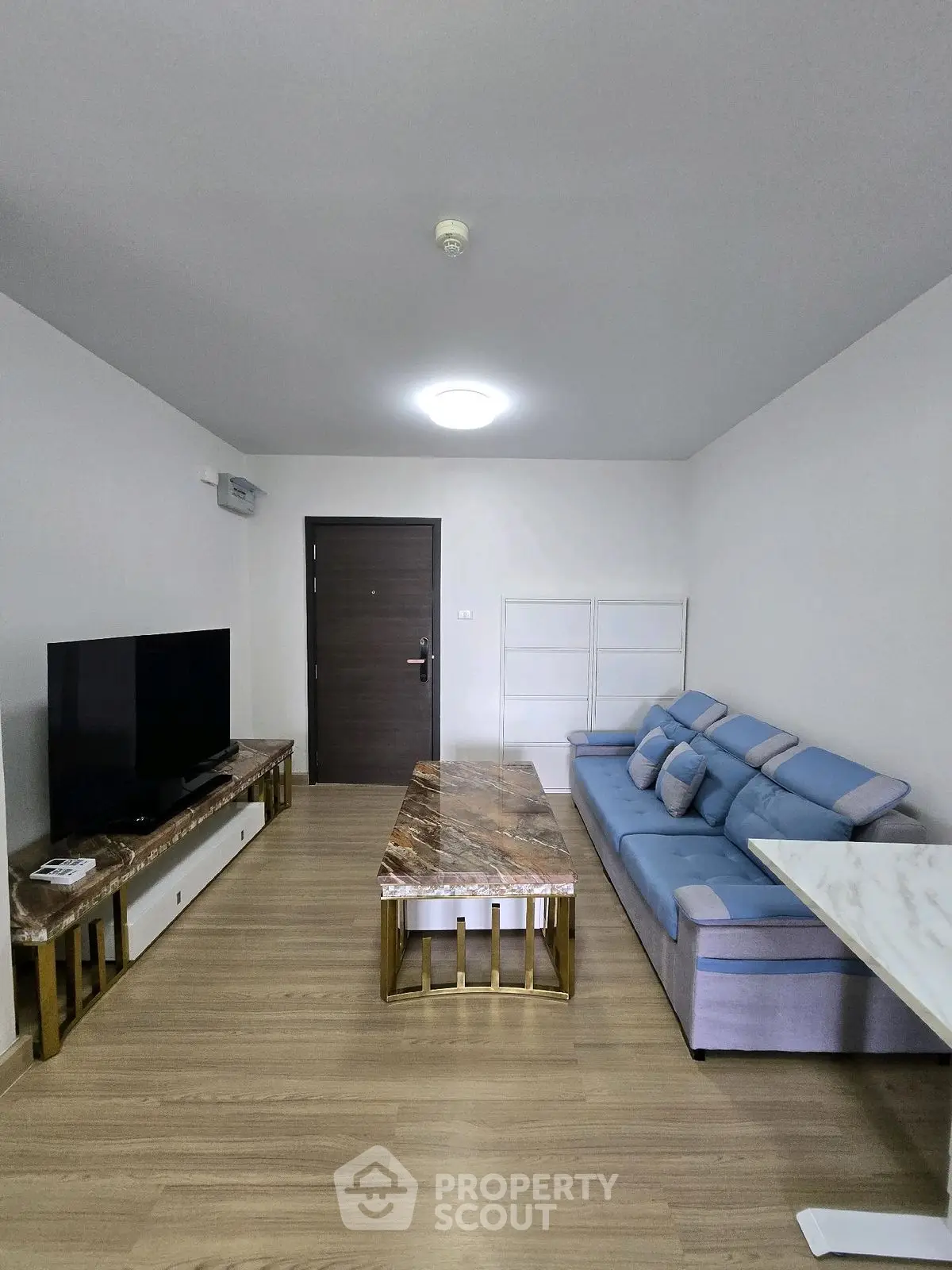 Modern living room with stylish marble coffee table and blue sofa, perfect for relaxation and entertainment.