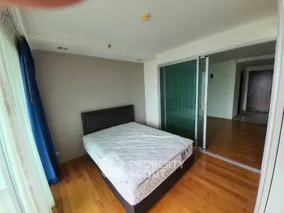 Spacious bedroom with wooden flooring and large windows for natural light