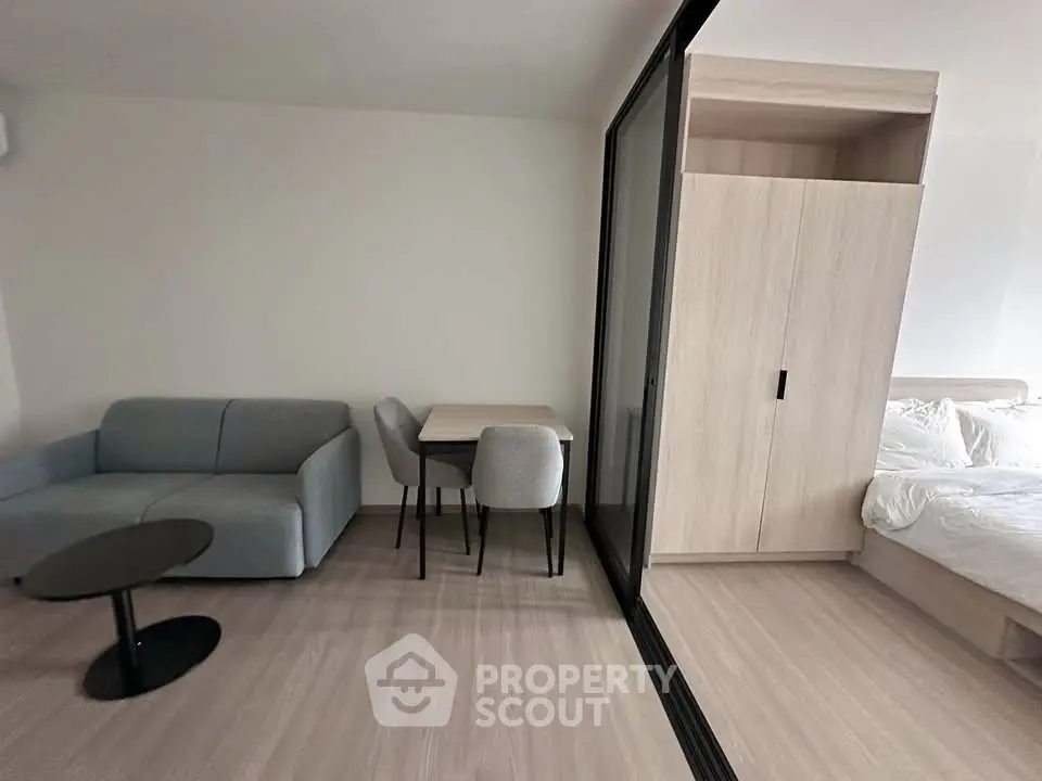 Modern studio apartment with cozy living area and sliding partition to bedroom.