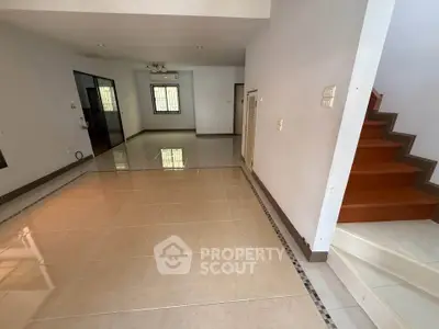 Spacious open-plan living area with tiled flooring and staircase, ideal for modern living.